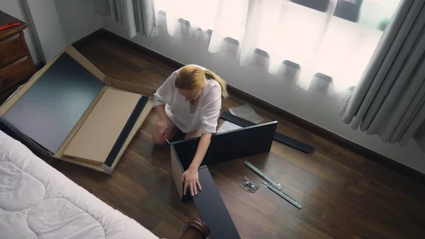 Möbel zu Hause zusammenbauen, eine Hausfrau baut einen Computertisch mit Handwerkzeugen zusammen. — Stockfoto