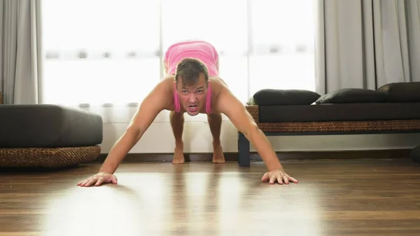 Игривый красавчик в розовой футболке занимается фитнесом, в гостиной своего дома . — стоковое фото