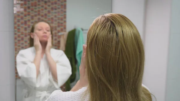 Encarar o conceito de cuidado. Mulher aplicando loção cosmética para cuidar da pele no banheiro. Limpeza matinal — Fotografia de Stock