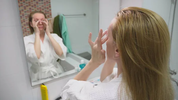 Concepto de cuidado facial. Mujer que aplica loción cosmética para cuidar la piel en el baño. Higiene matinal — Foto de Stock