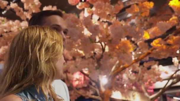 Beau couple d'amoureux est debout dans le centre commercial au milieu des paysages, sakura florissante — Video