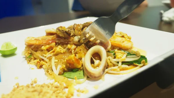Närbild. någon äter en maträtt av asiatisk mat på en restaurang. — Stockfoto