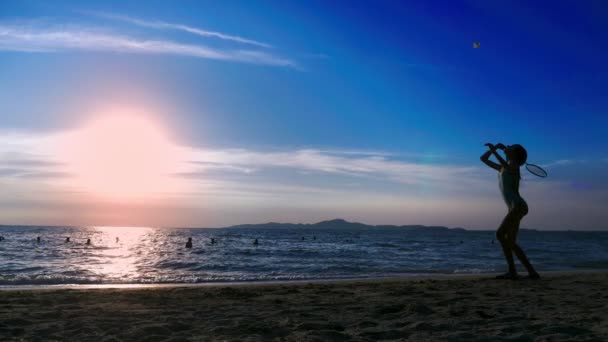 Силуэты. люди играют в бадминтон на пляже на закате . — стоковое видео