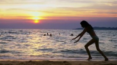 gün batımında, deniz, ince uzun bacaklı kız deniz kıyısında jimnastik darbeler yapıyor komik çerçevede bir kız silüeti