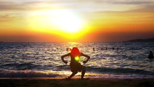 Silueta de un niño en el fondo de la puesta de sol del mar, divertido adolescente bailando en el fondo de una puesta de sol en el mar — Vídeo de stock