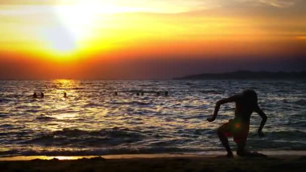 剪影一个男孩在海日落的背景, 滑稽的少年男孩在日落的背景下跳舞在海的背景下 — 图库视频影像
