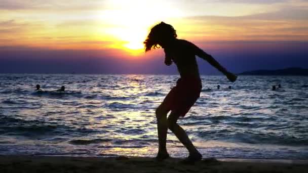 海の夕日の背景に少年のシルエット海の日没の背景の上で踊って面白いティーンエイ ジャーの男の子 — ストック動画