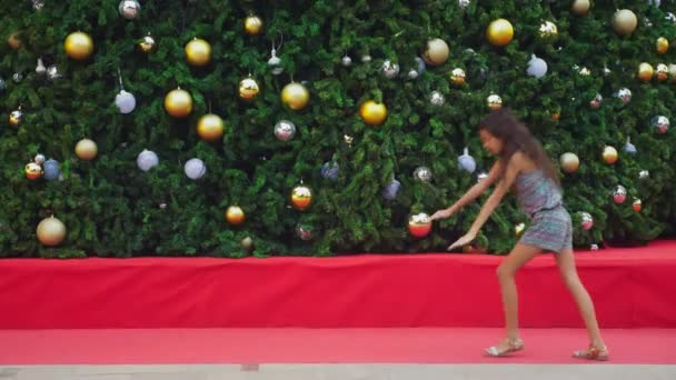 Счастливая девушка, занимающаяся гимнастическим сальто на фоне елки и пальм в тропическом городе. Концепция новогоднего путешествия в теплые страны . — стоковое видео