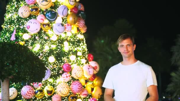 Счастливый человек на фоне елки и пальм в тропическом городе. Концепция новогоднего путешествия в теплые страны . — стоковое видео