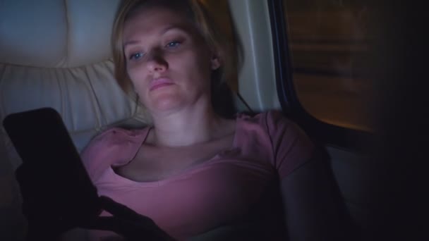 Una mujer cansada monta la noche en el autobús, usa su teléfono . — Vídeo de stock
