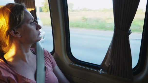 Грустная задумчивая девушка едет на автобусе и смотрит в окно  . — стоковое видео