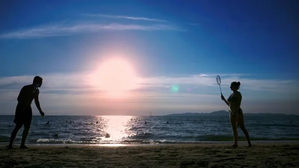 Silhuetter. personer spela badminton på stranden vid solnedgången. — Stockfoto