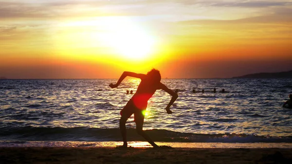 Sylwetka chłopca na tle sea zachód słońca, śmieszne nastolatek chłopiec taniec na tle zachodu słońca nad morzem — Zdjęcie stockowe