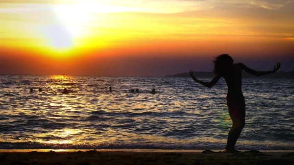 Silueta de un niño en el fondo de la puesta de sol del mar, divertido adolescente bailando en el fondo de una puesta de sol en el mar — Foto de Stock