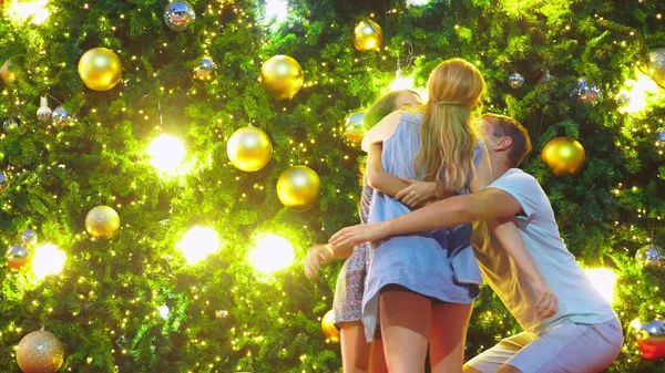 Ευτυχισμένη οικογένεια, ο μπαμπάς, μαμά και κόρη πληρούν τη νέα χρονιά στο φόντο του το χριστουγεννιάτικο δέντρο σε ένα τροπικό πόλη. Η έννοια της Πρωτοχρονιάς ταξιδεύουν σε θερμές χώρες — Φωτογραφία Αρχείου