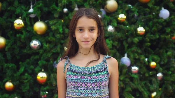 熱帯都市のヤシの木とクリスマス ツリーの背景に幸せな女の子。新しい年の概念は暖かい国へ旅行します。. — ストック写真