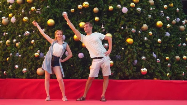 Casal feliz homem e mulher dançando no fundo da árvore de Natal em uma cidade tropical. O conceito de viagens de Ano Novo a países quentes . — Fotografia de Stock