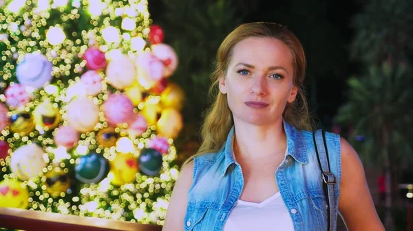 Donna felice sullo sfondo dell'albero di Natale e delle palme in una città tropicale. Il concetto di Capodanno viaggia in paesi caldi . — Foto Stock