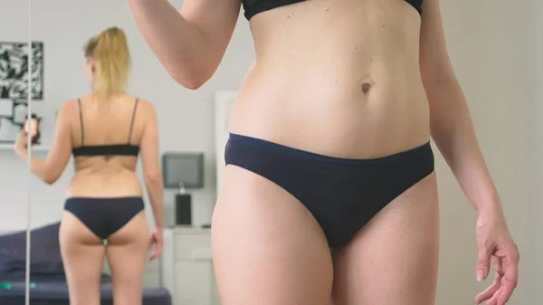太りすぎや体重減少の概念。女性は鏡で自分を見て、彼女の姿の写真します。前に、と減量後の結果を比較するには. — ストック写真