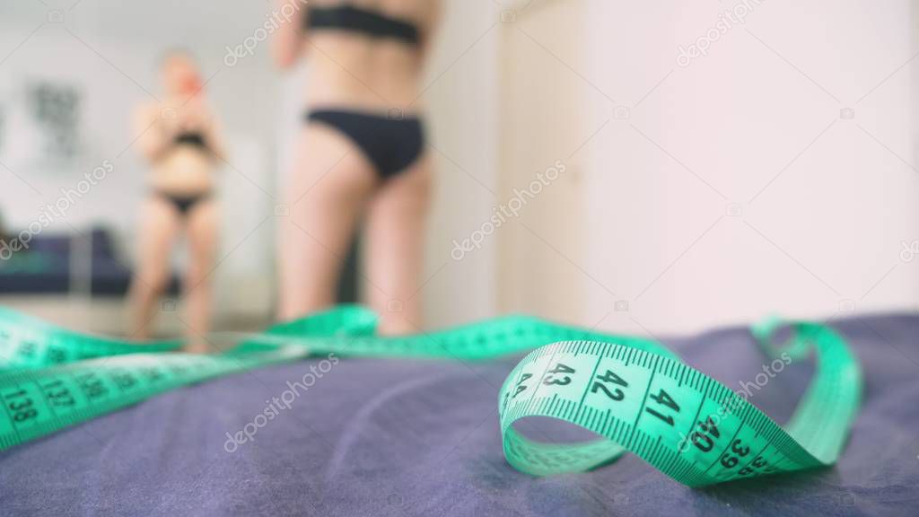 The concept of overweight and weight loss. A woman looks at herself in the mirror and photographs her figure. to compare the results before and after losing weight.