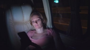 Yorgun bir kadın gece otobüse biner, telefonunu kullanın.