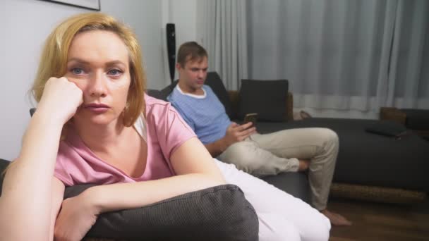 Пара проблем. Мужчина и женщина проводят вечер в гостиной на диване. мужчина пользуется телефоном, женщина расстроена тем, что он не обращает на нее внимания . — стоковое видео