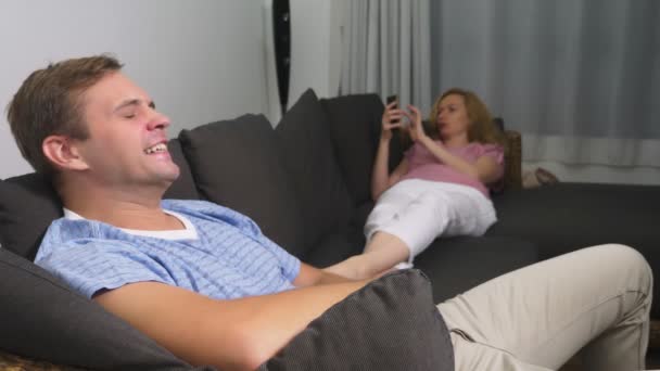 Paarkrise. Mann und Frau verbringen den Abend im Wohnzimmer auf der Couch. die Frau telefoniert, der Mann ärgert sich, dass sie nicht auf ihn achtet. — Stockvideo