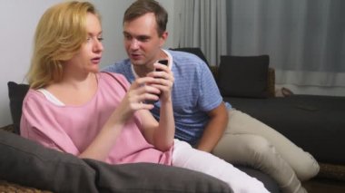 İki kriz. Erkek ve kadın oturma odasında kanepede akşamın. bir kadının telefonunu kullanır ve erkekler flört yok sayar.
