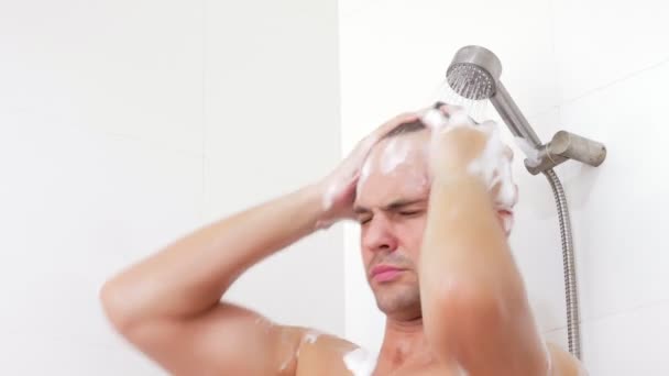 Joven lavando el cabello bajo la ducha.El hombre se lava el pelo en casa . — Vídeo de stock