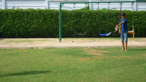 Ein jugendlicher Junge und ein Mädchen spielen Badminton auf einem grünen Rasen im Hinterhof ihres Hauses — Stockvideo