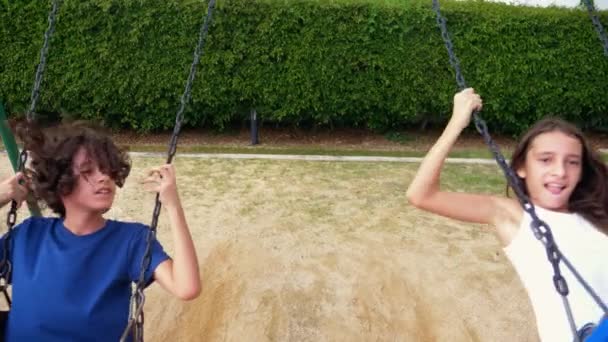 Boy and girl teenager swinging on a swing with bare feet on the green lawn of the backyard of his house — Stock Video