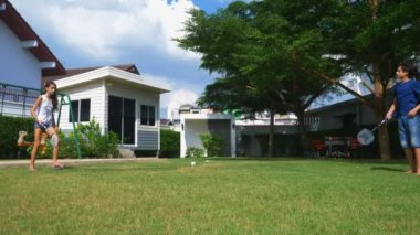 Bir genç erkek ve kız badminton kendi arka bahçesinde bir yeşil çim üzerinde oynamak