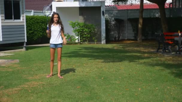 Un adolescente y una niña juegan bádminton en un césped verde en el patio trasero de su casa — Vídeos de Stock