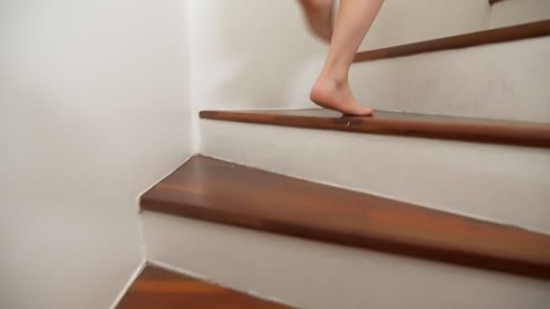 Primo piano. gambe femminili sale in cima a una scala di legno. donna in vestaglia cammina sui gradini — Video Stock