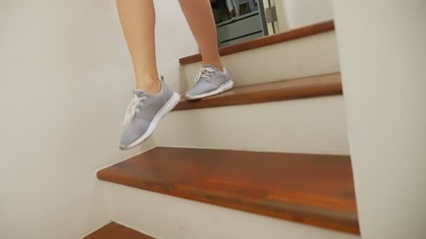 Piernas femeninas en zapatillas que corren a lo largo de una escalera de madera — Vídeos de Stock