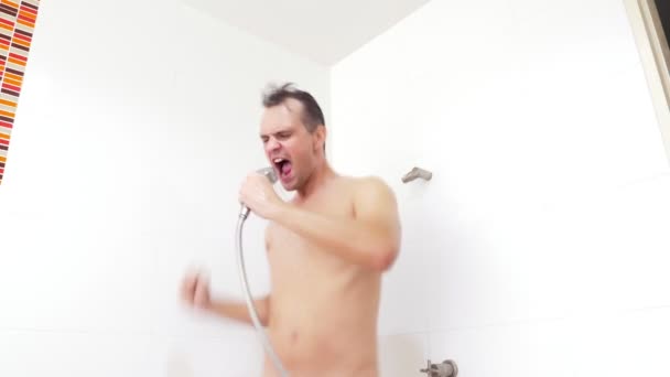 Joven guapo musculoso toma una ducha. el tipo lava, canta y baila en la ducha . — Vídeo de stock
