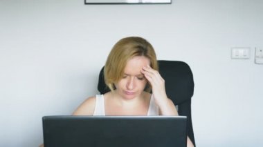 Onu laptop kullanan bir kadın masada, kızgın ve rahatsız oturur. İnsan duyguları. Internet bağımlılığı