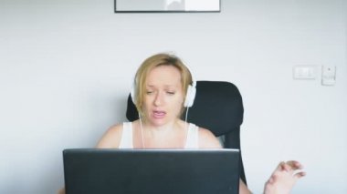Onu laptop kullanan bir kadın masada oturan, gülen ve konuşuyor. İnsan duyguları. Internet bağımlılığı.