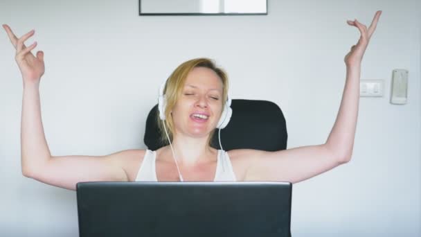 Eine Frau sitzt mit ihrem Laptop am Tisch, lacht und redet. Menschliche Emotionen. Internetsucht. — Stockvideo