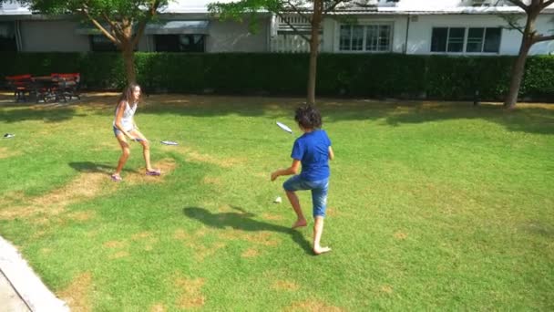 ティーンエイ ジャーの男の子と女の子は、彼らの家の裏庭の緑の芝生でバドミントンします。 — ストック動画