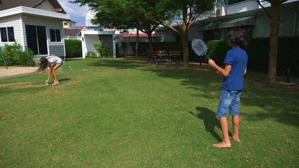 Dospívající chlapec a dívka hrát badminton na zelený trávník na zahradě jejich domu — Stock fotografie