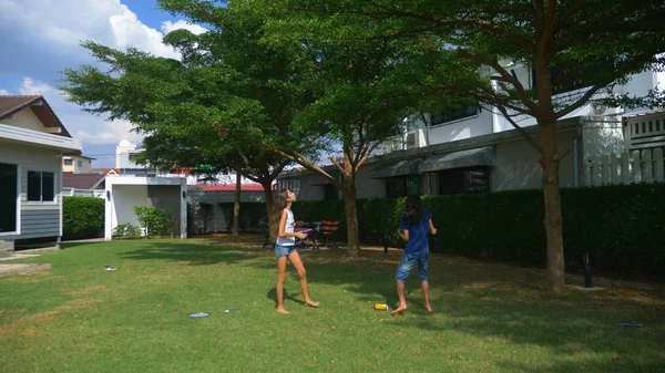 En tonåring pojke och flicka spela badminton på en grön gräsmatta i trädgården av deras hem — Stockfoto