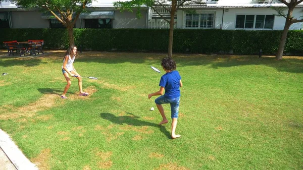 Bir genç erkek ve kız badminton kendi arka bahçesinde bir yeşil çim üzerinde oynamak — Stok fotoğraf