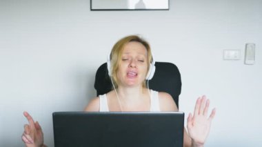 Onu laptop kullanan bir kadın masada oturan, gülen ve konuşuyor. İnsan duyguları. Internet bağımlılığı.