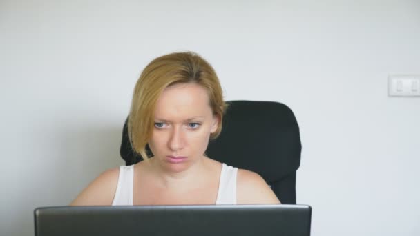 Bir dizüstü bilgisayar kullanan bir kadın masada oturur, hissediyor umutsuzluk ve ağlamaya başlar. İnsan duyguları. Internet bağımlılığı. — Stok video