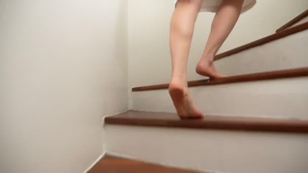 Γκρο πλαν. γυναικεία πόδια υψώνεται στην κορυφή του μια ξύλινη σκάλα. γυναίκα σε μια ρόμπα βόλτες μέχρι τα βήματα — Αρχείο Βίντεο