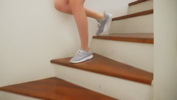 Piernas femeninas en zapatillas que corren a lo largo de una escalera de madera — Vídeos de Stock