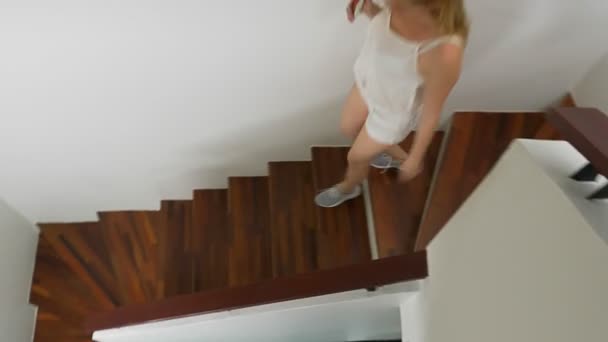 Ragazza in pantaloncini cammina scale a casa e utilizza uno smartphone — Video Stock