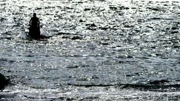 Desportos aquáticos. silhueta, um homem em uma moto flutua no mar . — Vídeo de Stock