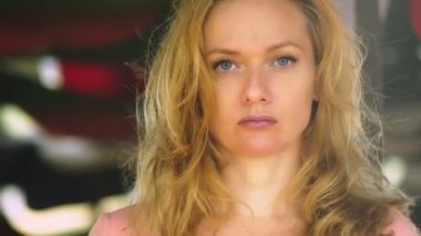 Sarı saçlı güzel bir genç kadınla dikkatle kameraya bakarak rüzgarlı bir günde notunuzda boş duruyor. kopya alanı